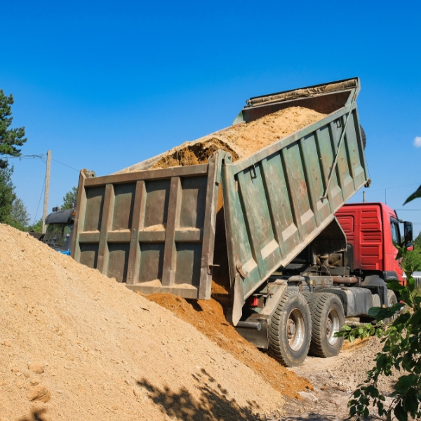 Image of a dump truck, a type of construction vehicle, dropping a load of soil.