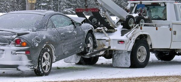Image of a light-duty wrecker tow truck pulling a car.